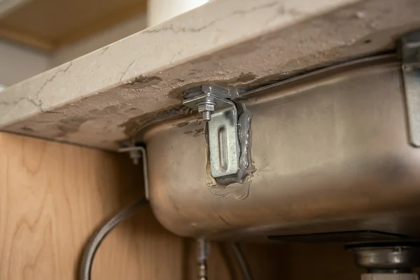 Undermount sink re-anchored with new clips under a quartz countertop